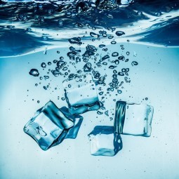 Ice cubes falling into the water sinking to the bottom. Abstract background.