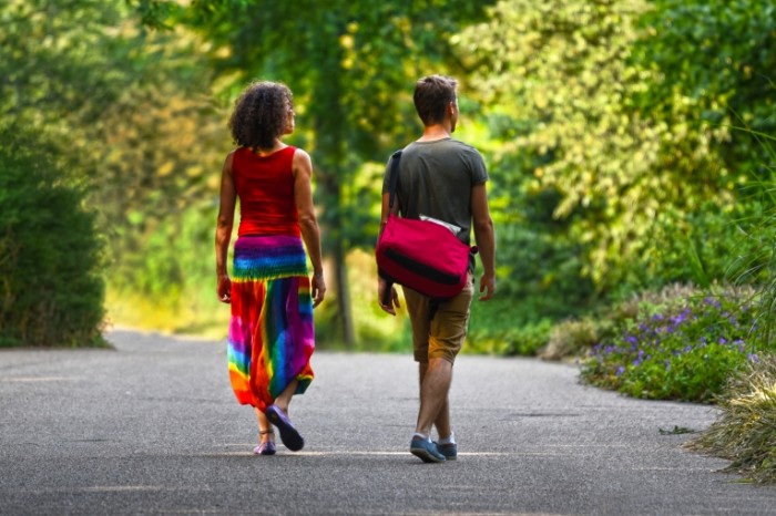 Пара гуляет в парке летом среди деревьев по асфальтовой дорожке - Couple walks in the park in the summer